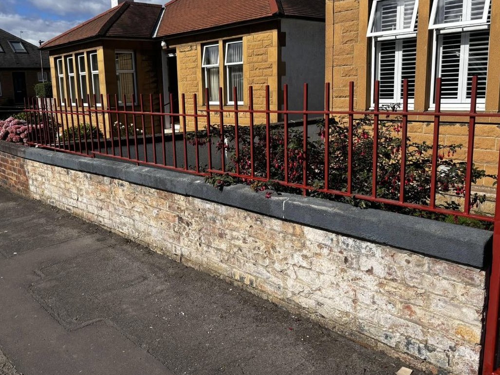 Red painted railings on a sandstone garden wall outside an Edinburgh bungalow